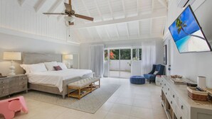A bedroom with a bed, bedside table, lamp, and a TV on the wall.
