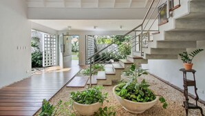 A modern interior with a staircase, potted plants, and a wooden deck.