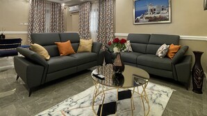 A living room with two grey sofas, a glass coffee table, and a marble-patterned rug. - JPN SQUARE Douala (Douala)