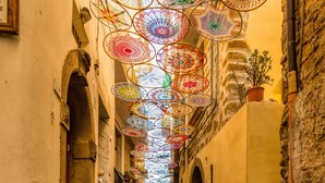 Eine Kopfsteinpflasterstraße mit bunten Regenschirmen, die darüber hängen.