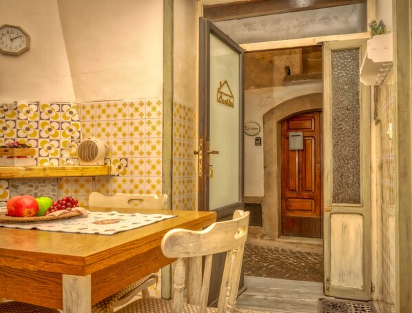 Un comedor con una mesa de madera, sillas y una cesta de frutas.