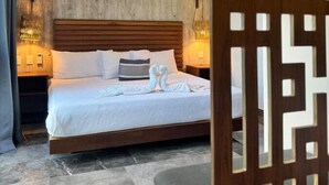 Et moderne hotelværelse med en trægavl, en pænt redt seng med hvide sengetøj og en dekorativ vægpanel.