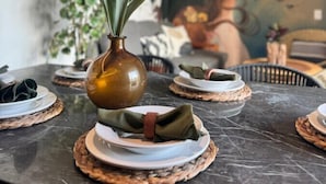 Et spisebord med tallerkener og en vase med grønne blade.