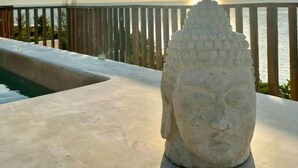 Una estatua de Buda en un balcón con vista al atardecer.