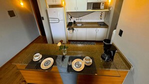 A compact kitchen with white cabinets, a microwave, and a coffee maker. - Saint Sebastian Flat 601Duplex no Centro (Jaragua do Sul)