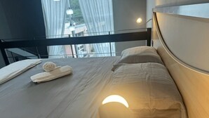 A modern hotel room with a large bed, a headboard, and a view through a window. - Saint Sebastian Flat 601Duplex no Centro (Jaragua do Sul)