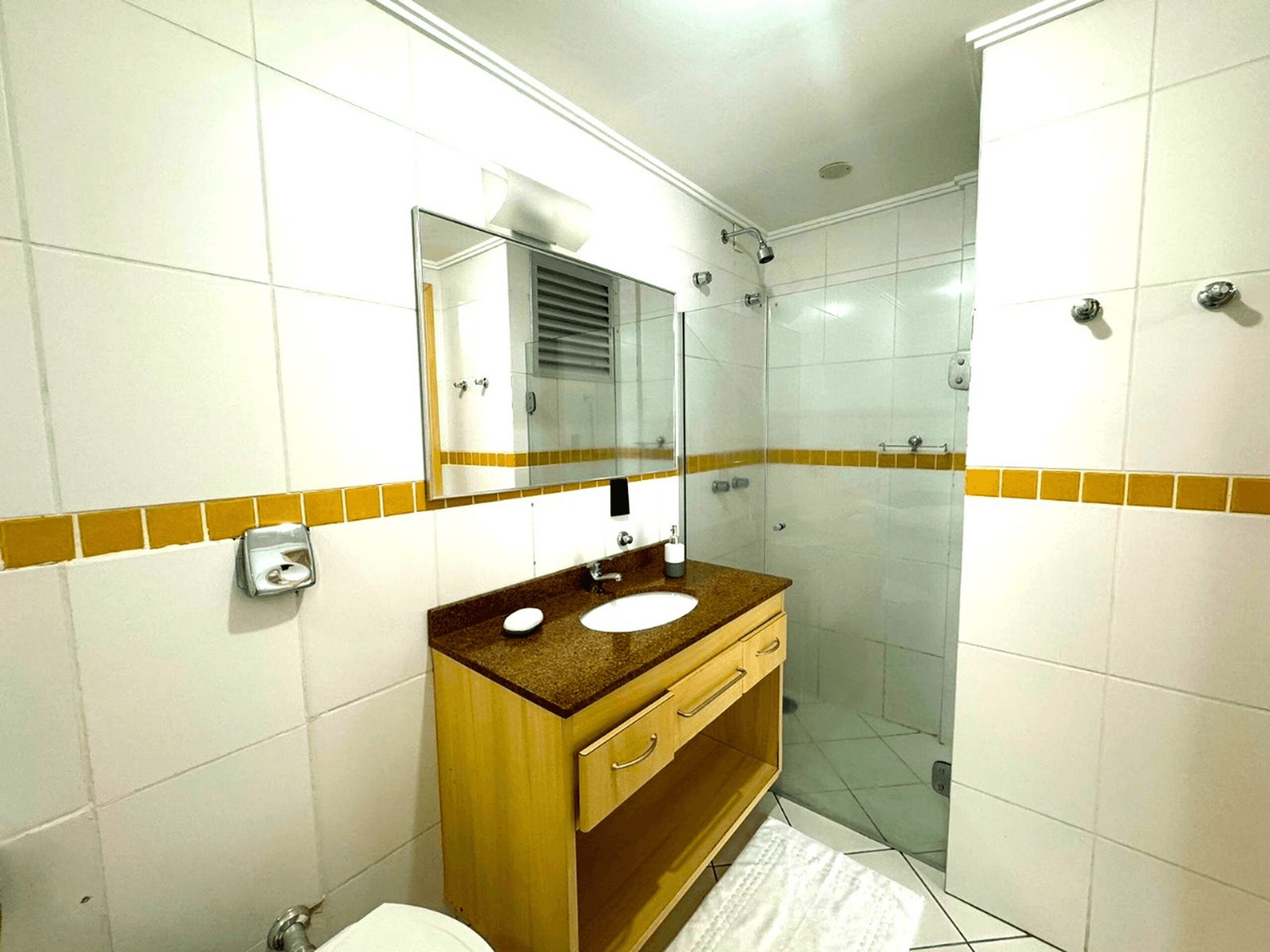 Un baño con lavamanos, espejo y ducha.