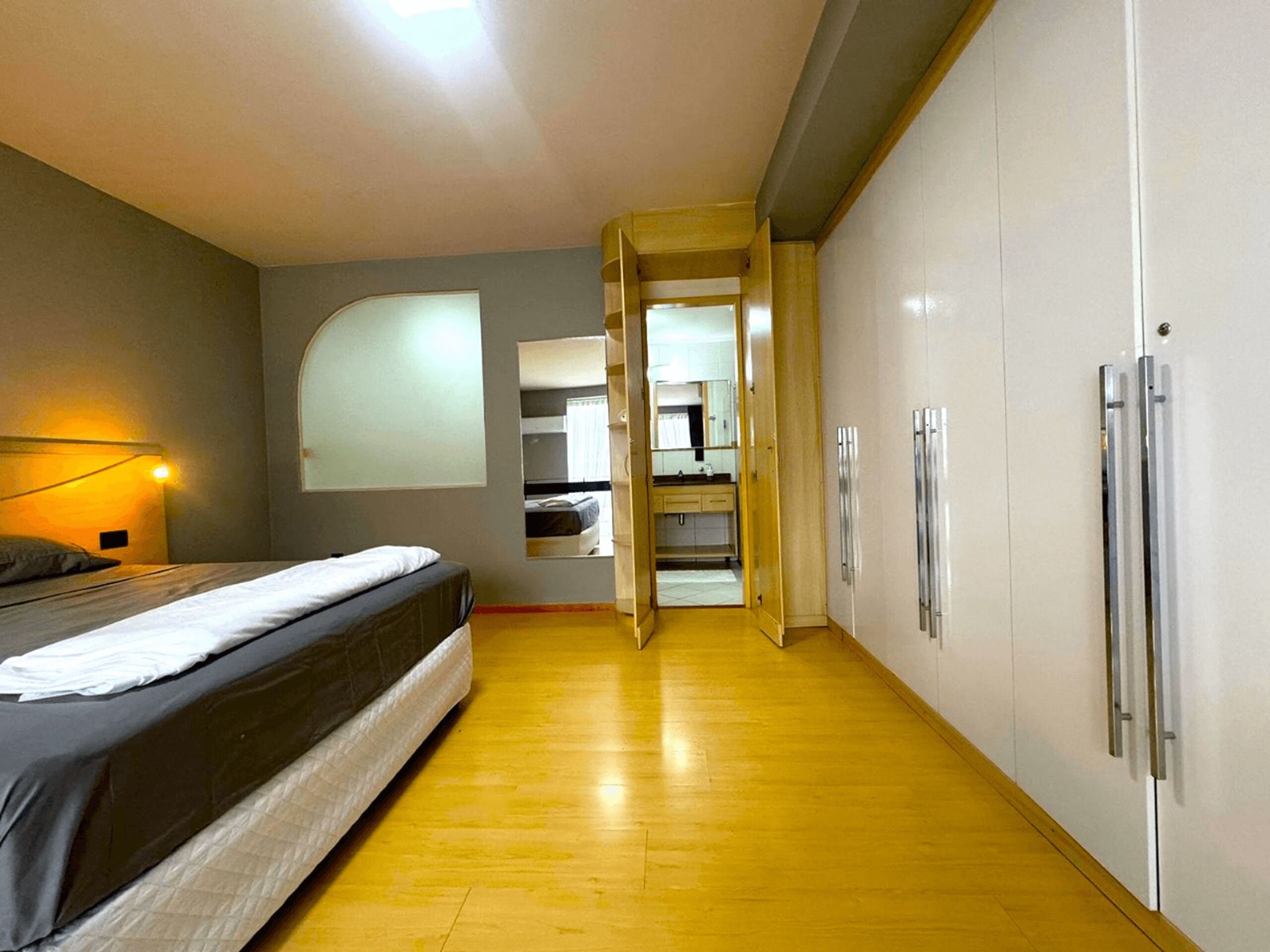 Una camera da letto con un letto, una lampada da comodino, un armadio e uno specchio.