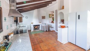 A kitchen with a stove, sink, and white refrigerator. There is a tiled backsplash and a window with curtains.