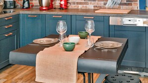 A modern kitchen with blue cabinets, a wooden countertop, and a dining table set with glassware and plates.