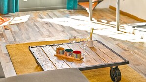 A wooden floor with a small table holding a tray with cups and a glass.