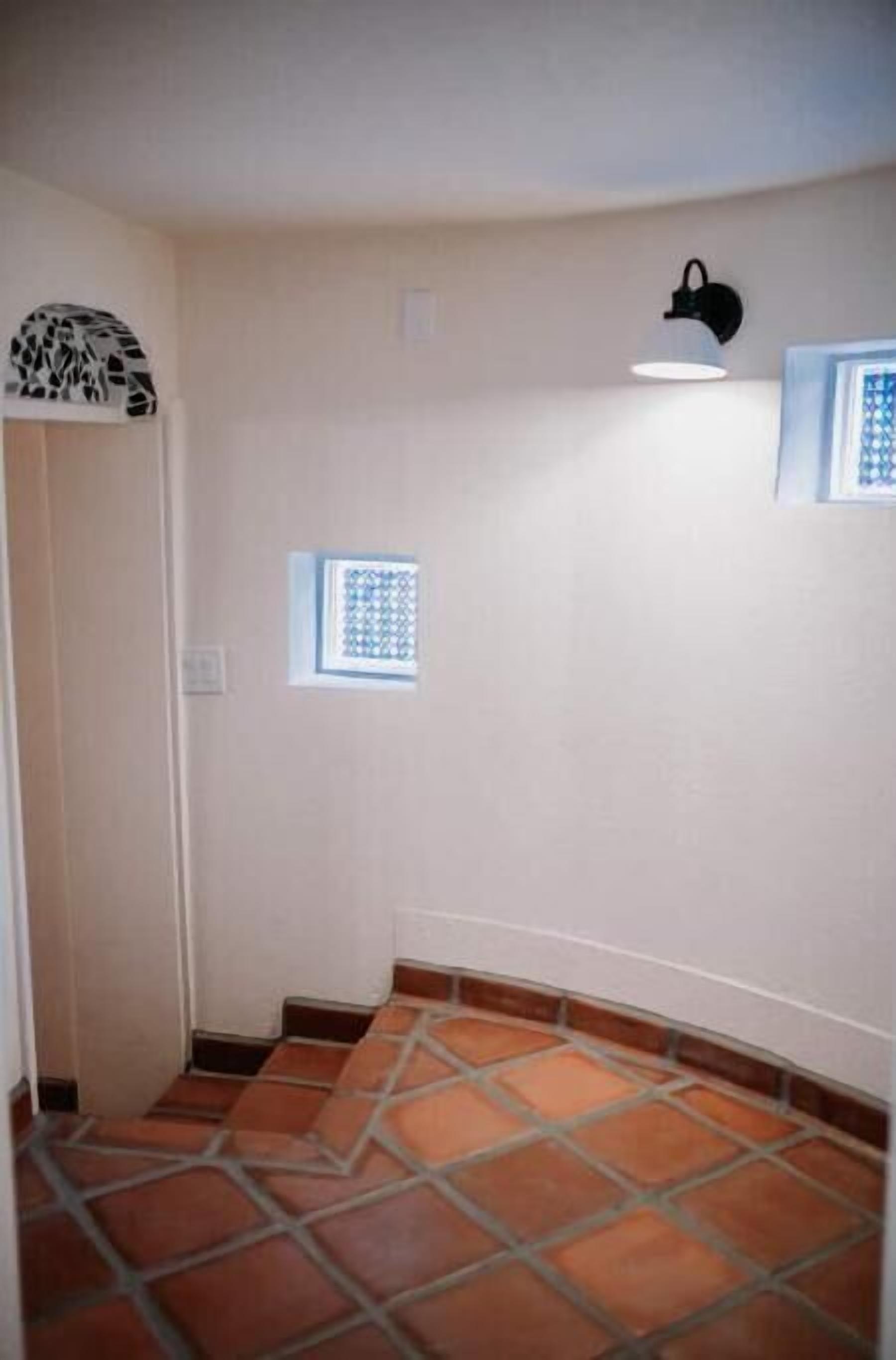 A room with a tiled floor, a small window, and a wall-mounted light fixture.