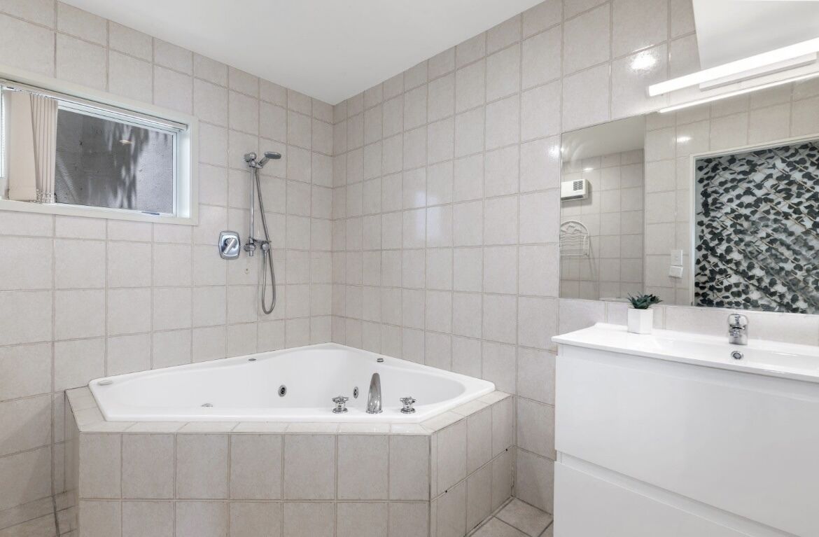 Ein modernes Badezimmer mit einer freistehenden Badewanne, einem großen Spiegel und einer gefliesten Duschkabine.