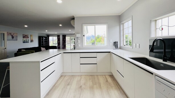A modern kitchen with white cabinetry, a black sink, and a window providing a view of greenery outside. - Lakeview Mountain-view 3BR Home close to Rotorua Centre (Rotorua)