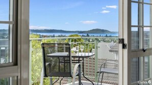 A balcony with a table and chairs, overlooking a scenic view of hills and a body of water. - Lakeview Mountain-view 3BR Home close to Rotorua Centre (Rotorua)