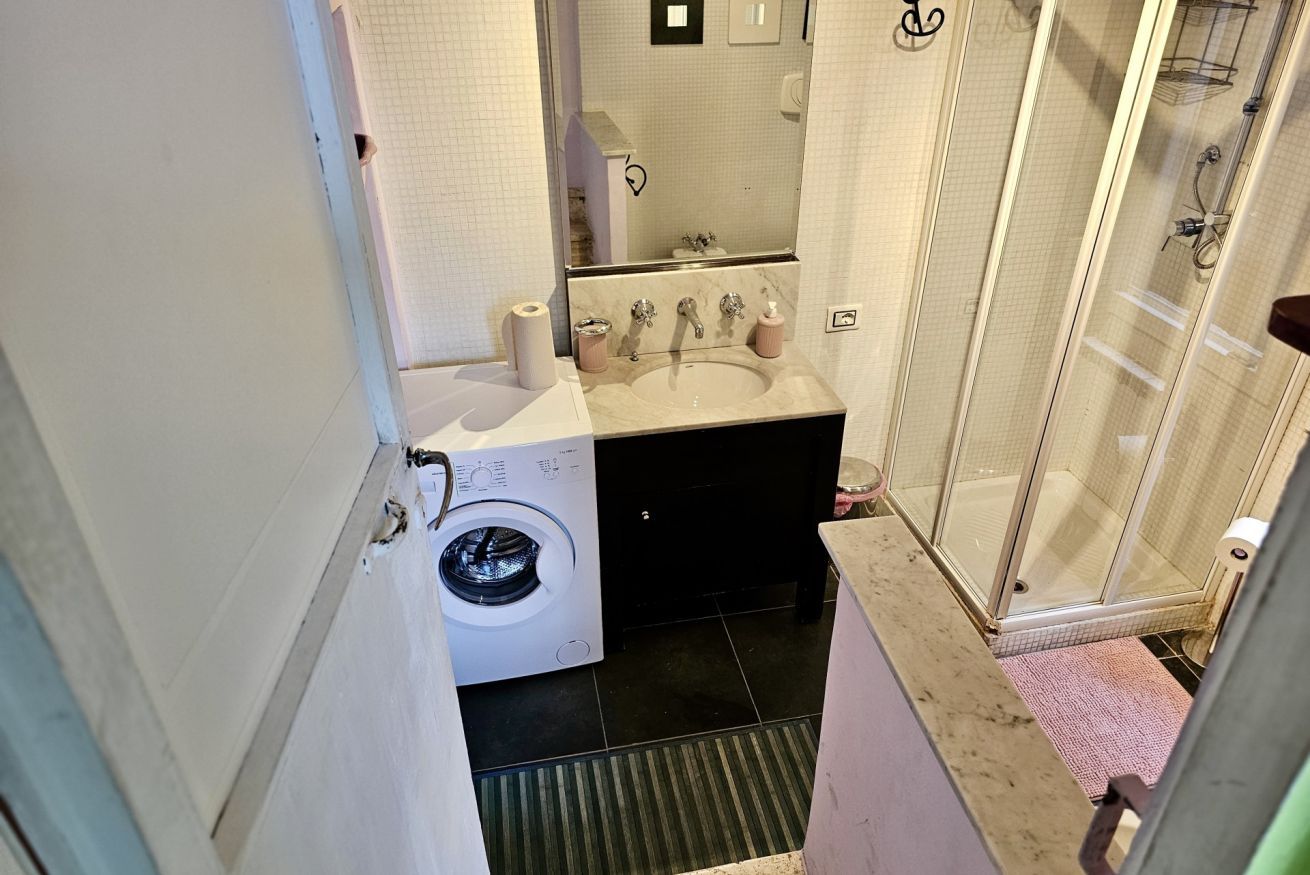 Ein kleines Badezimmer mit Waschmaschine, Waschbecken und einer Duschkabine.