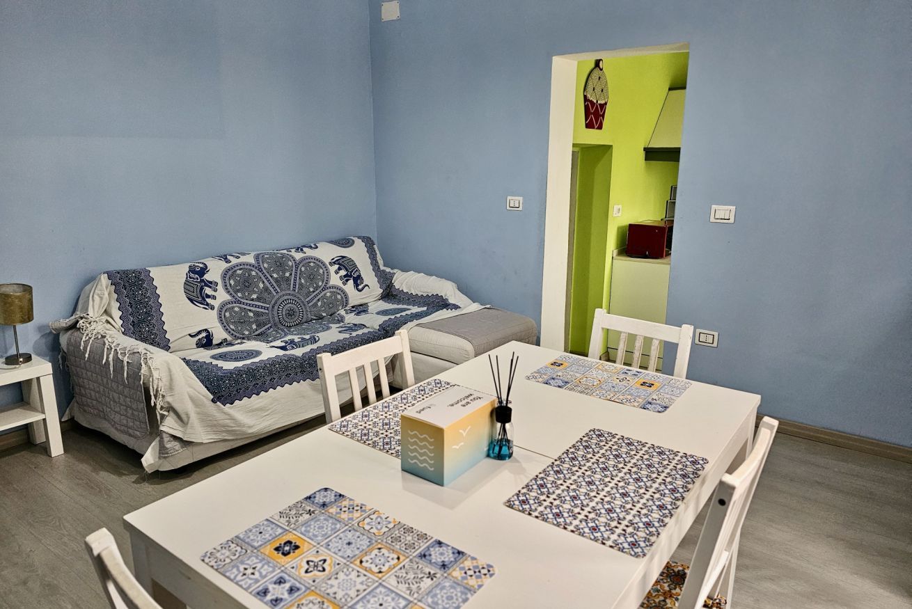 Una stanza con un letto, un tavolo con una scatola e bastoncini di incenso, e una sedia.