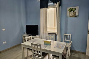 A dining area with a table, chairs, a television, and a window with curtains. - SE045 - Senigallia, three-room apartment convenient to services (Senigallia)