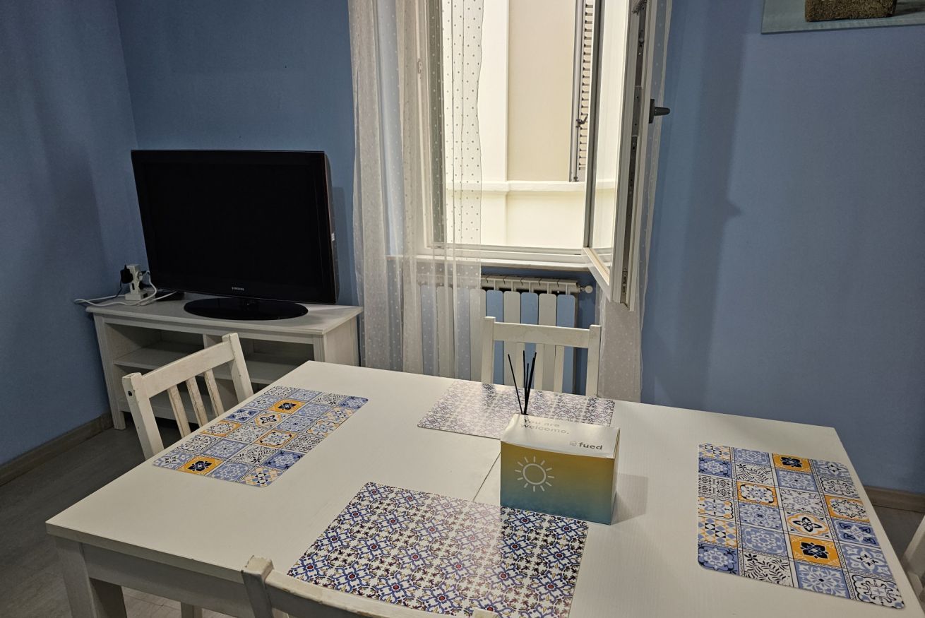 Ein Zimmer mit einem weißen Tisch, einem Fernseher und einem Fenster mit Vorhängen.