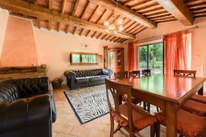 A rustic interior with a wooden ceiling, leather sofa, dining table, and a zebra-patterned rug.