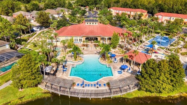 An aerial view of a resort with a central swimming pool, multiple buildings, and a surrounding natural landscape. - Private patio and hot tub in Terra Verde Resort (Kissimmee)