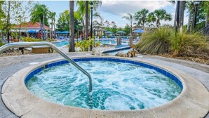 A hot tub surrounded by palm trees and a pool area with lounge chairs. - Private patio and hot tub in Terra Verde Resort (Kissimmee)