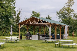 A covered outdoor area with picnic tables and barbecue equipment. - Battenkill Glamping Resort (Cambridge)