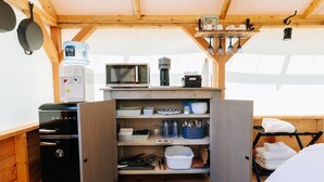 Une cuisine compacte équipée d’un réfrigérateur Galanz, d’un four à micro-ondes et d’une machine à café, le tout placé sur une étagère en bois.