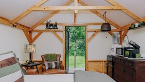 L’intérieur d’un chalet accueillant, avec un lit, une chaise, une petite table, une lampe, un four à micro-ondes et un distributeur d’eau.