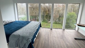 A bedroom with a large window, a bed, and a wooden floor. - 3 Story Rainbow Riverfront House With Panoramic Views!  (Dunnellon)