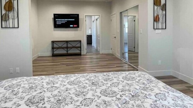Une chambre à coucher avec un lit, un téléviseur fixé au mur et une console.