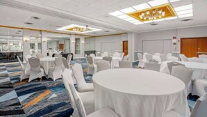 A conference room with round tables and white chairs, a patterned carpet, and a chandelier. - Best Western New Brunswick - East Brunswick (East Brunswick)