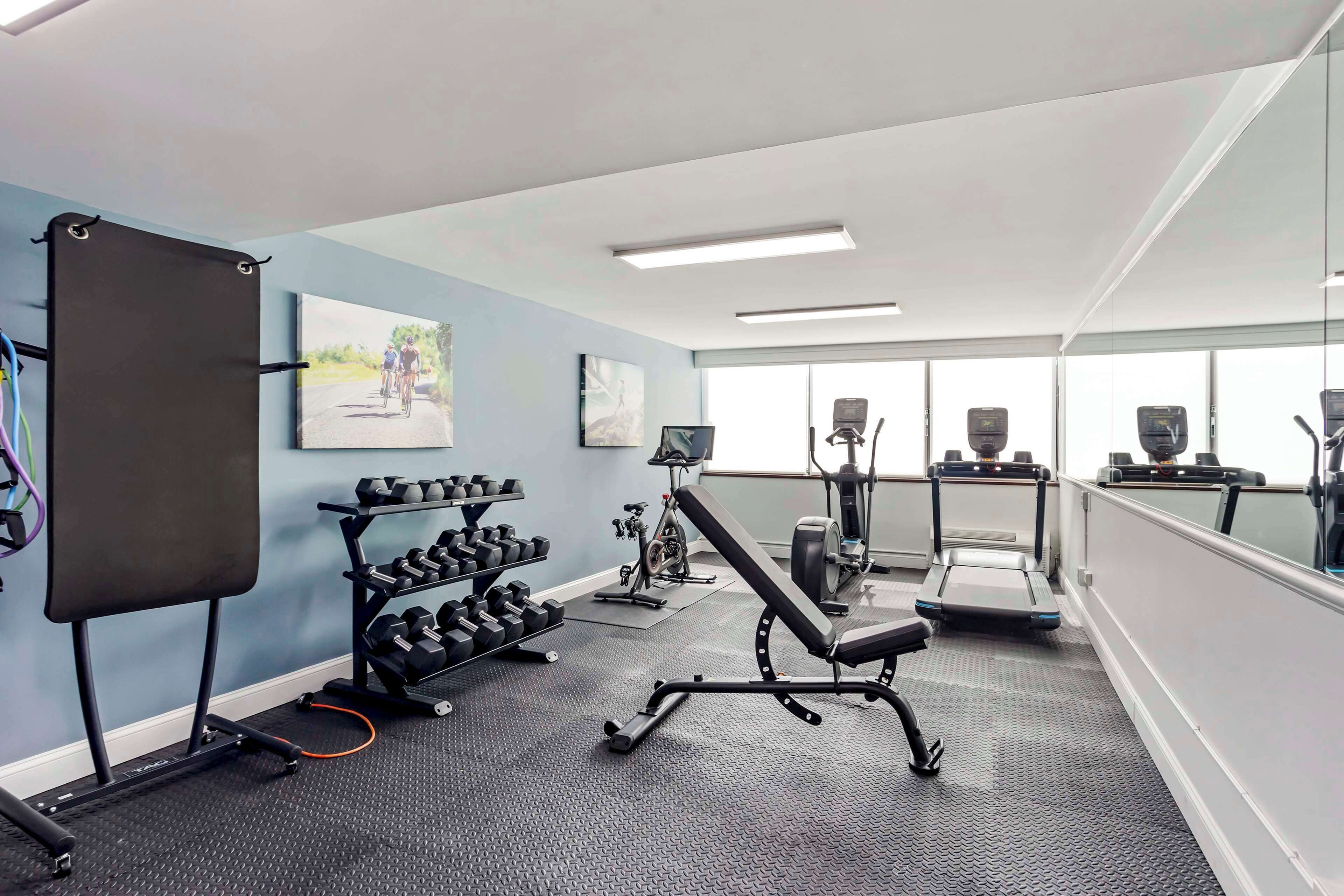 A gym with exercise equipment, dumbbells, and a treadmill.