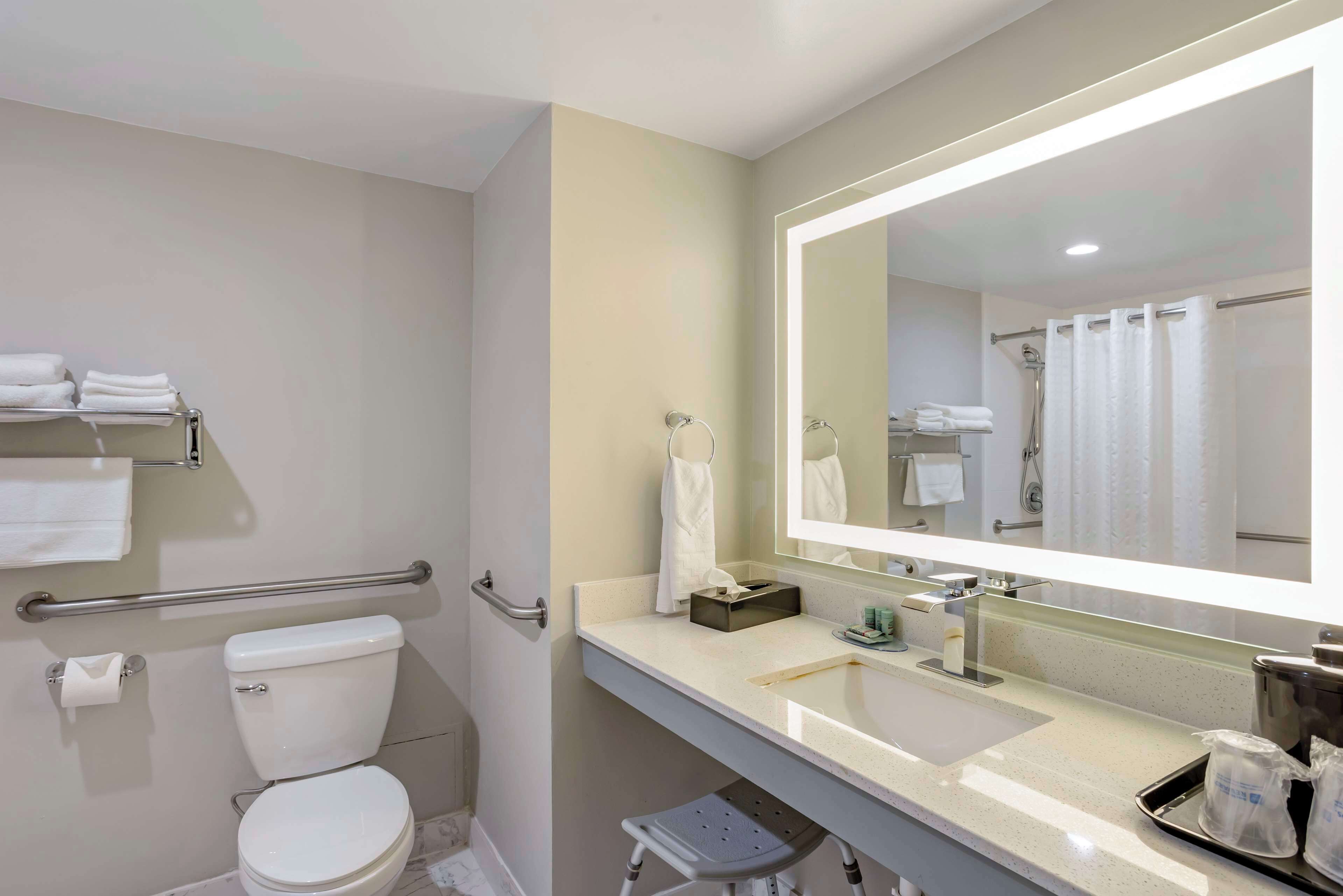 Een moderne badkamer met toilet, wastafel en grote spiegel.