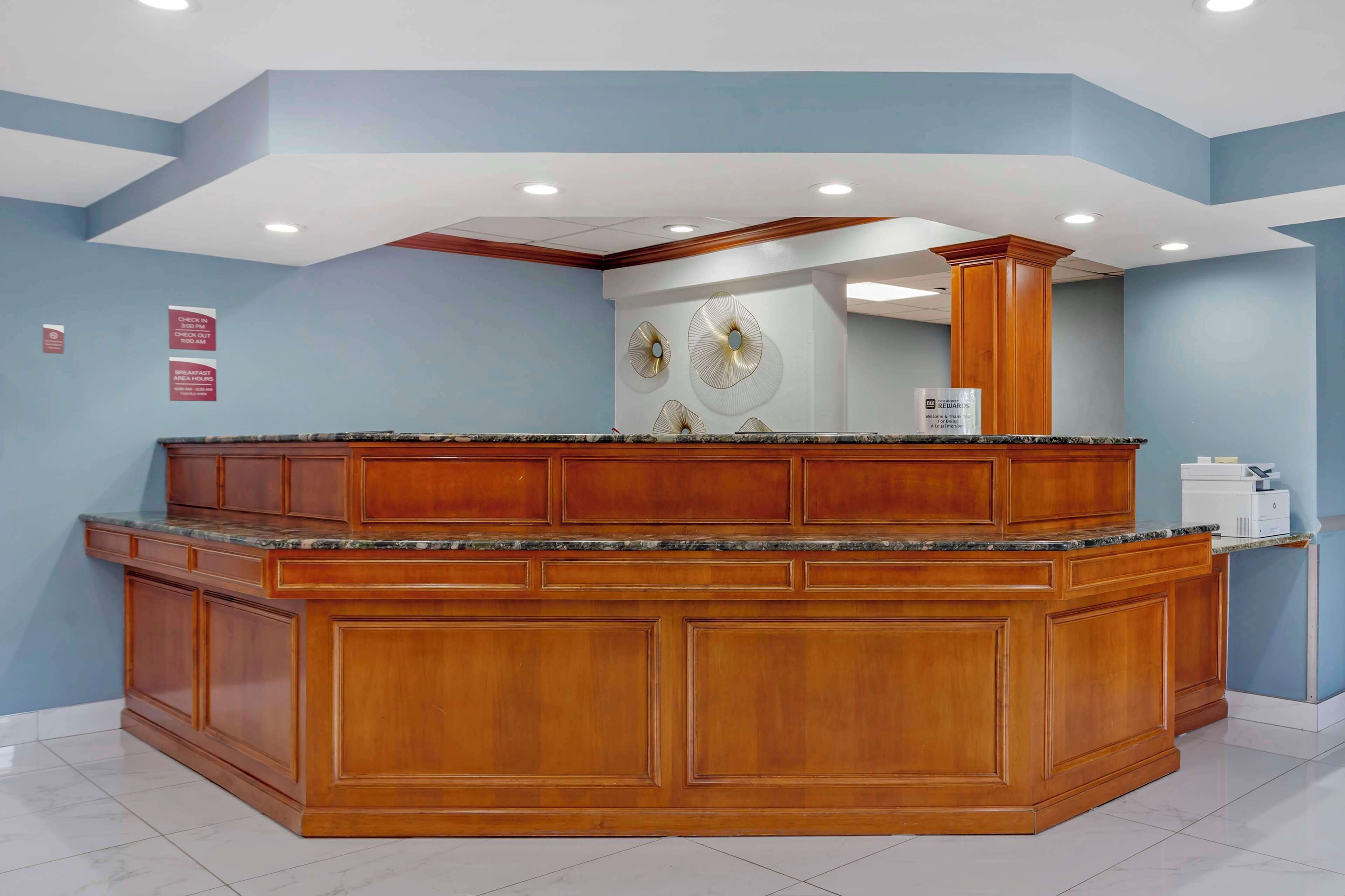A reception area with a wooden counter and a large mirror.