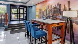 A hotel lobby with a cityscape mural, a reception desk, and blue bar stools. - Best Western New Brunswick - East Brunswick (East Brunswick)