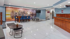 A hotel lobby with a reception desk, a seating area with chairs and a table, a cityscape mural on the wall, and a staircase in the background. - Best Western New Brunswick - East Brunswick (East Brunswick)