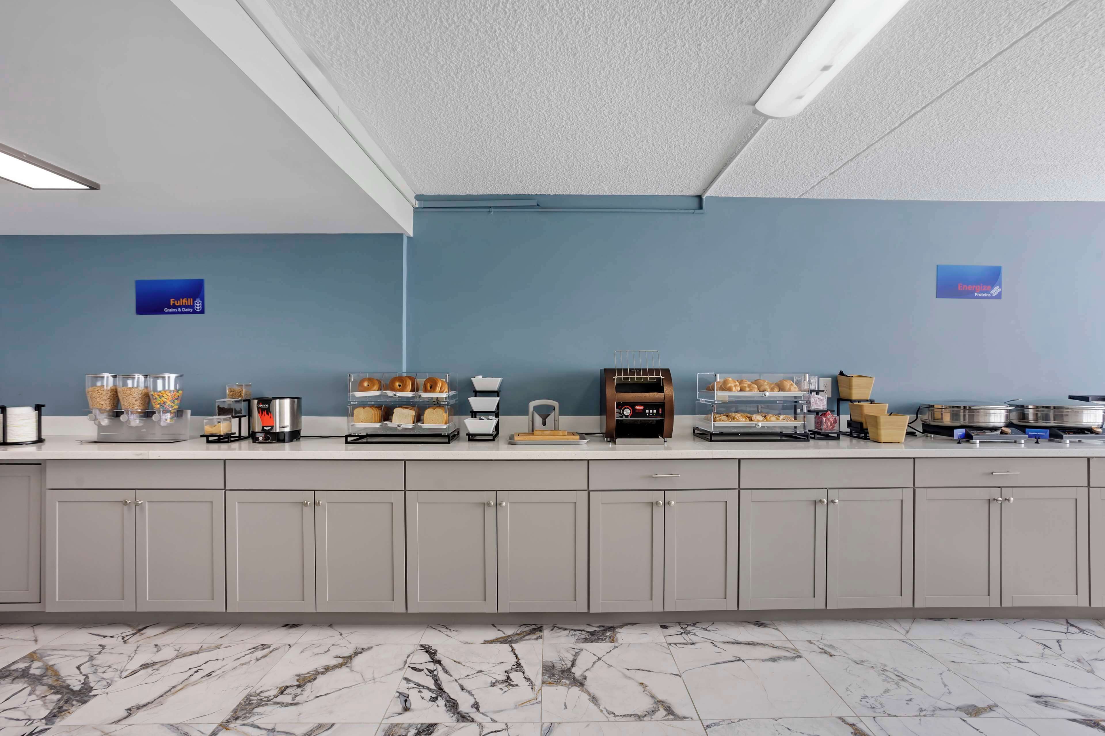 A kitchen area with a marble floor, a blue wall, and various kitchen appliances and utensils.