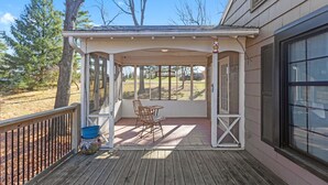 Eine überdachte Veranda mit Tisch und Stühlen, einem blauen Eimer und einer Ziervase.