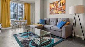 A modern living room with a sofa, coffee table, and a painting on the wall. - City View 1BR Downtown Calgary (Calgary)