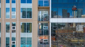 A modern building with multiple floors, large windows, and a glass facade reflecting the cityscape. - City View 1BR Downtown Calgary (Calgary)