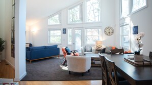 A spacious living room with a large window, a ceiling fan, and a dining area with a table and chairs.