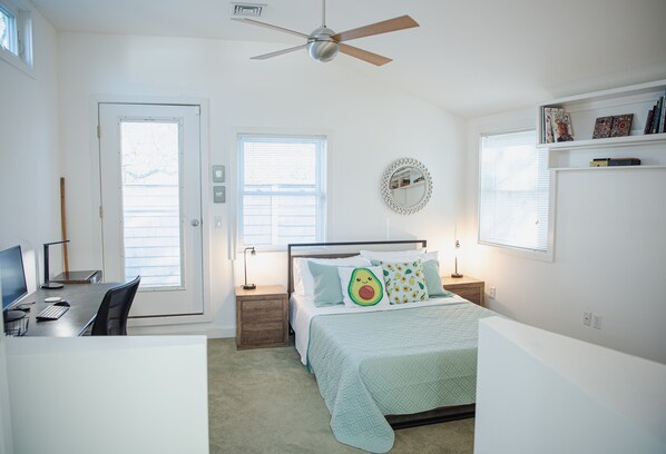 A bedroom with a bed, desk, chair, and a ceiling fan.