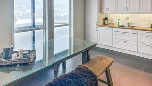 A modern kitchen with white cabinets, a glass-top table, and a bench. - Nice home in Rysstad with WiFi (Rysstad)