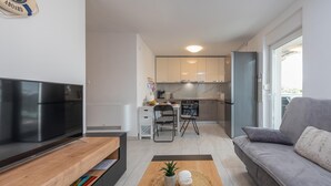 Un salon moderne avec un téléviseur à écran plat, un canapé et une table basse agrémentée d’objets décoratifs.