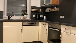 Eine moderne Küche mit Geschirrspüler, Backofen und Kaffeemaschine.