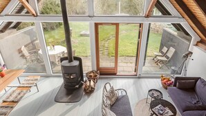 Un espacio de sala de estar moderno y de concepto abierto, con estufa de leña, zonas de estar y ventanas amplias que ofrecen vistas al exterior.