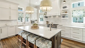 A spacious kitchen with a large island, white cabinetry, and a farmhouse sink. - Park Place 251 LAU (Port Aransas)