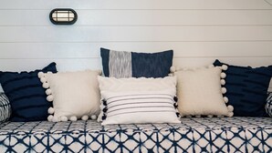 Un sofá con funda de estampado geométrico, tres almohadones decorativos y una lámpara de pared.