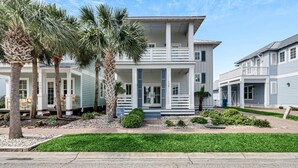 A two-story house with a porch, palm trees, and a well-maintained lawn. - Cloud Nine 136 BE (Port Aransas)